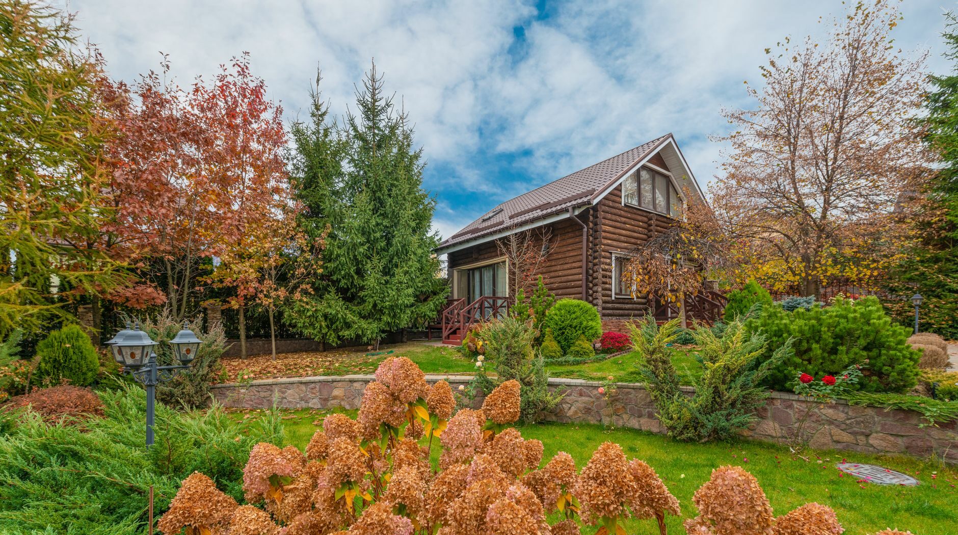 A picturesque log cabin surrounded by vibrant autumn foliage in a scenic garden setting.